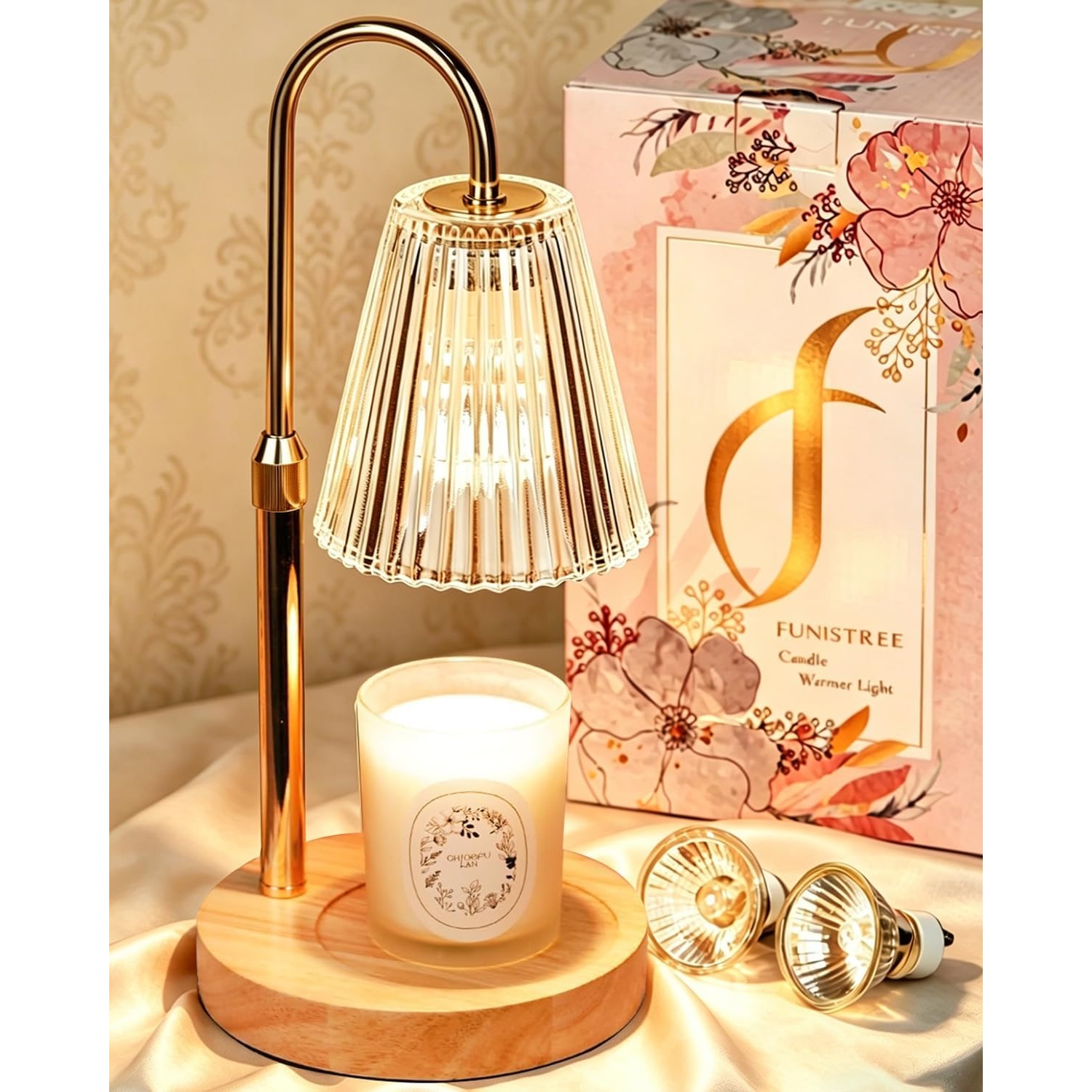 Gold candle warmer lamp with a ribbed glass shade glowing over a white jar candle